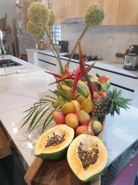 Corbeille de fruits tropicaux sur le plan de la cuisine : papayes ouvertes, mangues, ananas et fleurs d'héliconia